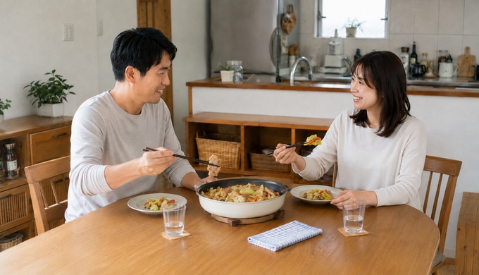 男女二人が食卓のフライパンから、豚肉やパプリカなど好みの具材をそれぞれ取り分けている。
