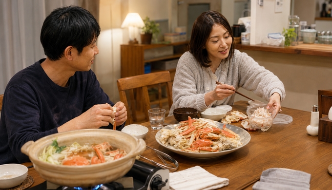 カニを囲む食卓で、食事の途中にカニの身を翌日用の器へ取り分けている様子。
